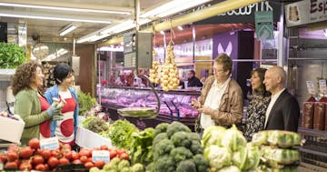 a person standing in front of a store filled with lots of fresh produce