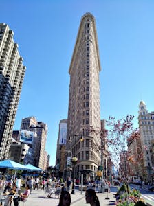 a group of people walking in front of a tall building with Flatiron Building in the background