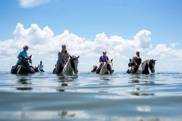 a group of people riding on horses in the water