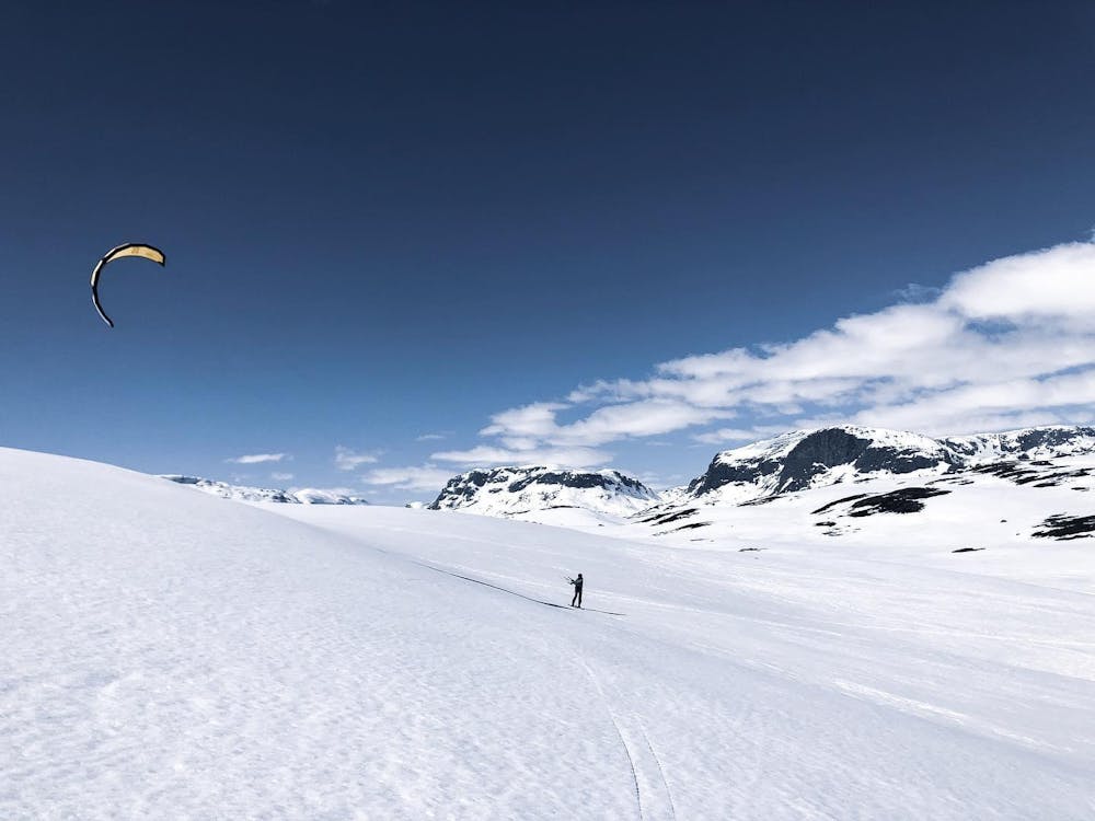 a group of people flying kites over a snow covered slope