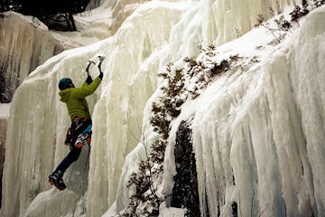 an ice climber ascending a frozen waterfall