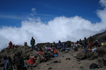 trekkers, guides, and local support staff rest high on Kilimanjaro's slopes