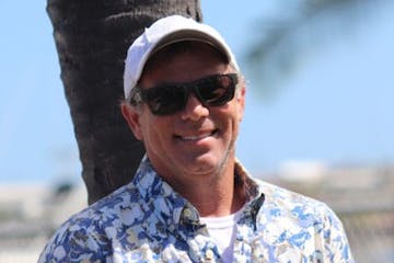 a man wearing a hat and sunglasses posing for the camera