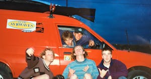 a group of people posing in front of a red van