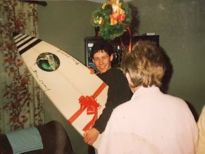 a young boy getting a christmas present of a surfboard