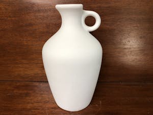 a white vase sitting on a wooden surface