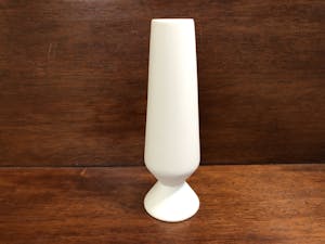 a white vase sitting on top of a wooden table