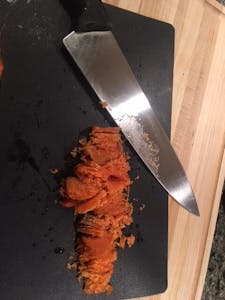a slice of salmon, now minced, on a cutting board with a knife