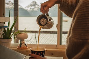 pouring a latte in our cafe space, with mountains in the background