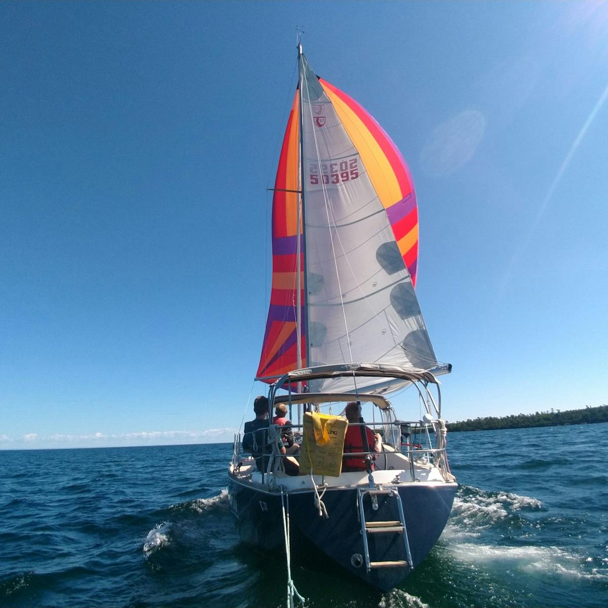 Under full sail, Vahevala's brightly colored spinnaker propels her to the horizon.