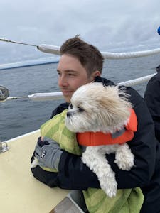 A man clutches a dog aboard a sailboat