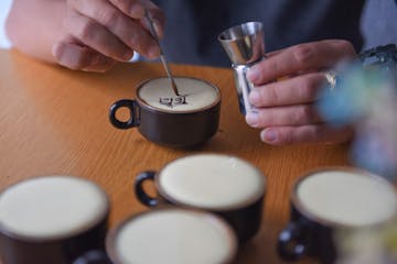 a hand holding a cup of coffee on a table