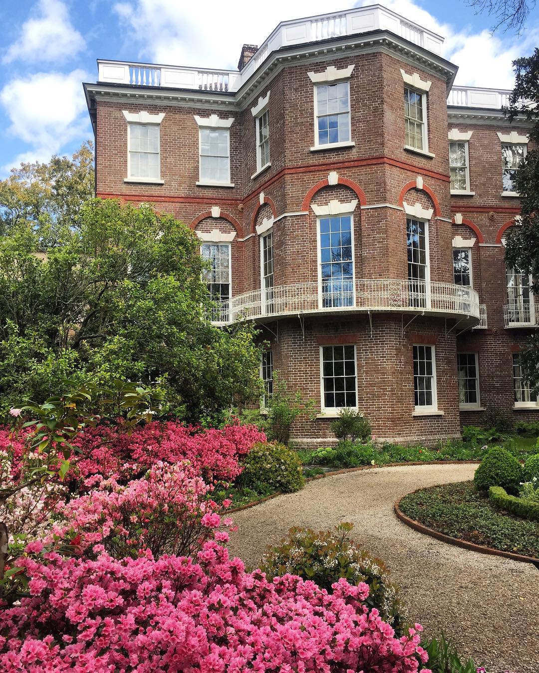 a large brick building with grass in front of a house with Wilberforce House in the background