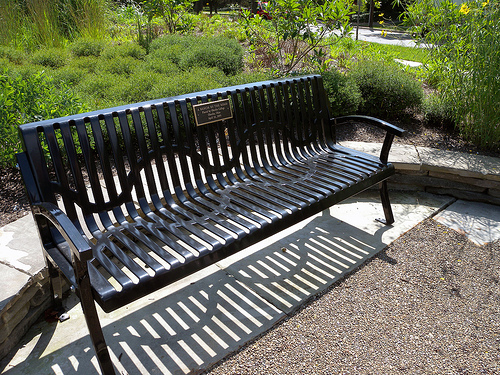 an empty park bench sitting on top of a wooden fence