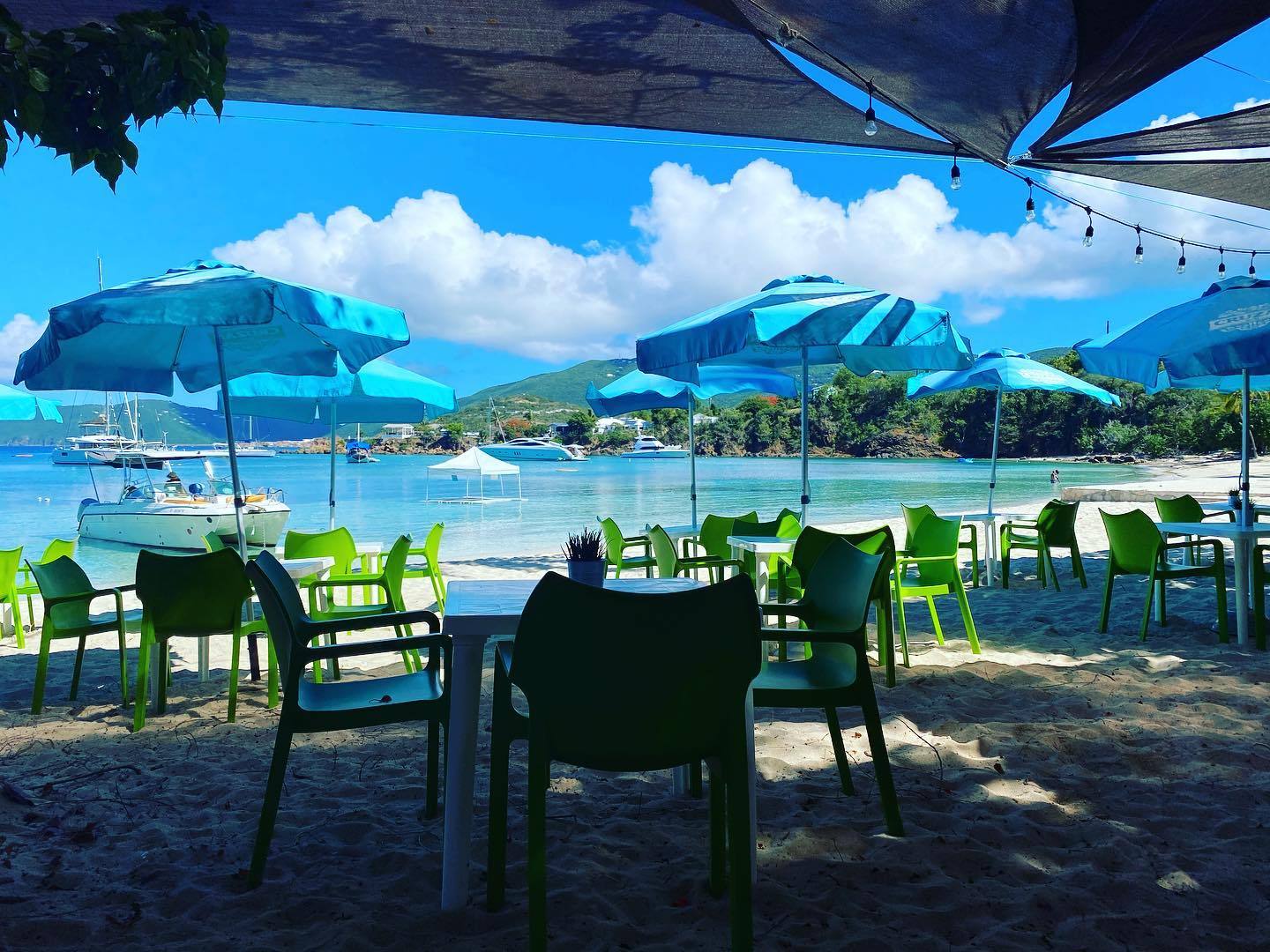 a lawn chair under an umbrella on a beach