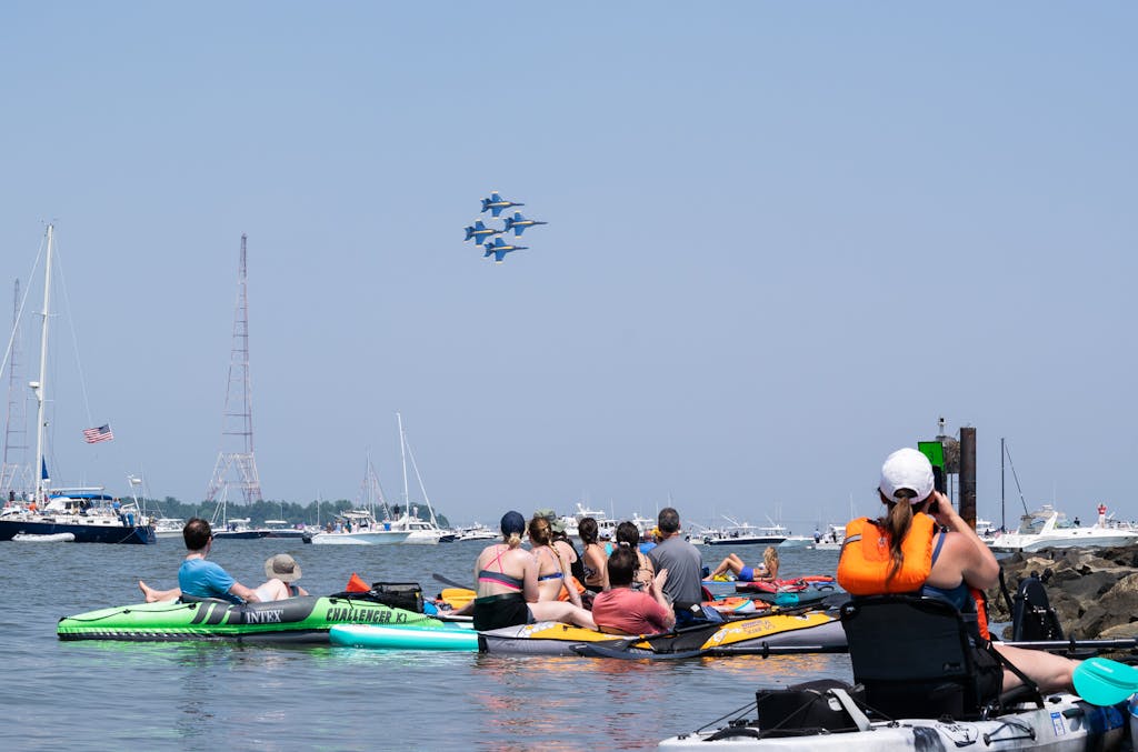 Blue Angels perform their air show over the severn river, people watch from the water on stand up paddle boards and kayaks