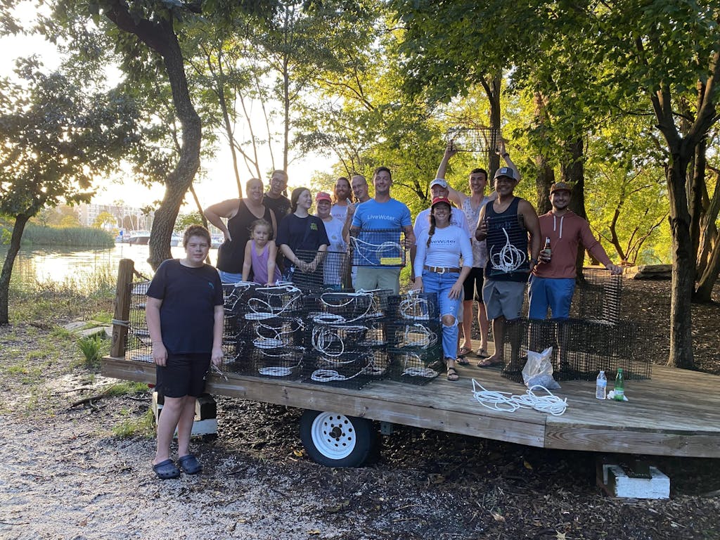 A group of volunteers stand next to stacks of oyster cages