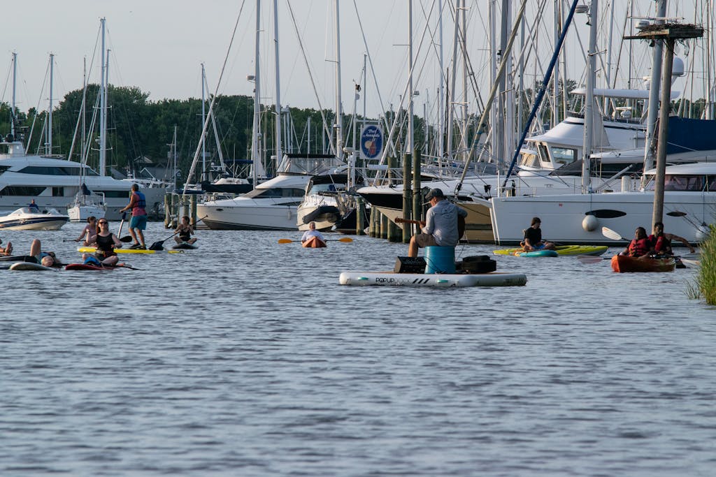 People in kayaks and on paddle boards watch musician Shawn Owen perform on a floating dock in Back Creek in Annapolis
