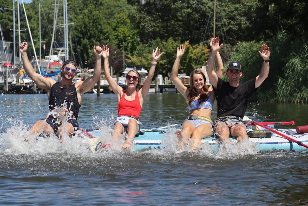 a group of people on a giant paddleboard party barge