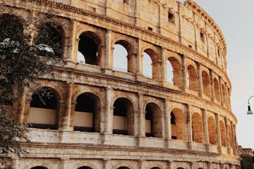 a large stone building with many windows with Colosseum in the background