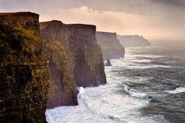 a man riding a wave on top of Cliffs of Moher