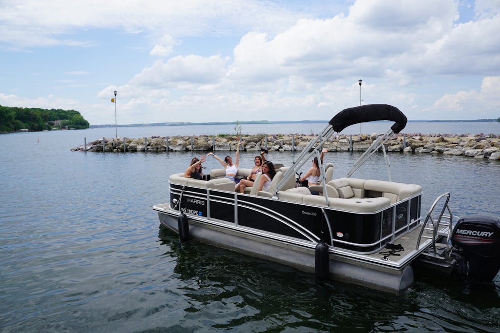 5 girls waving on a pontoon boat rental on lake mendota