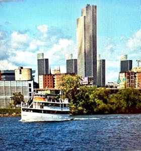 a large ship in a body of water with a city in the background
