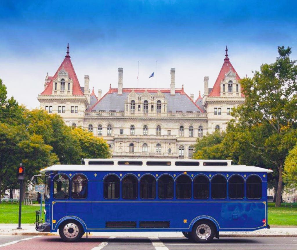 a blue bus parked in front of New York State Capitol