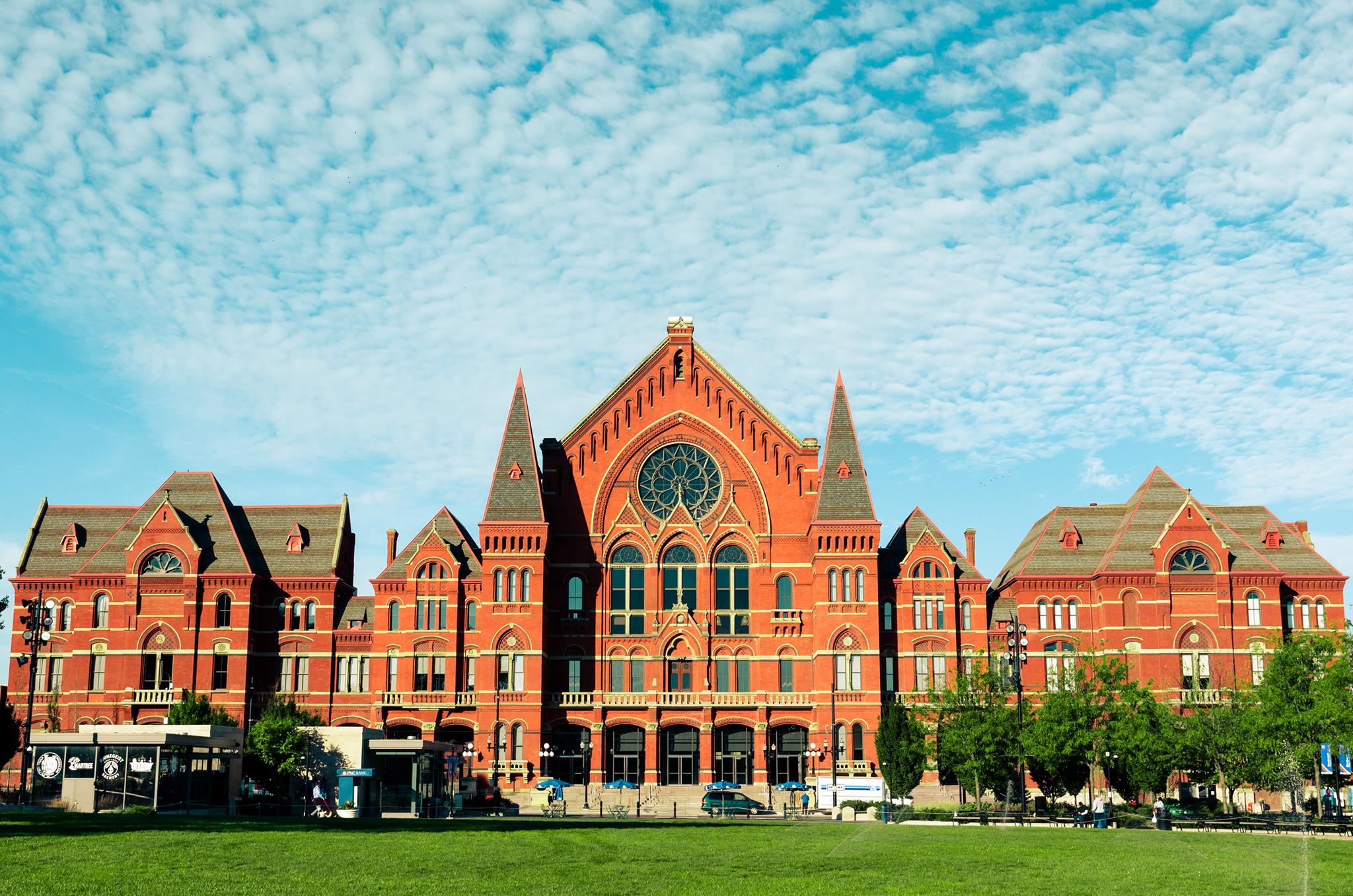 a large brick building with grass in front of a house with Cincinnati Music Hall in the background