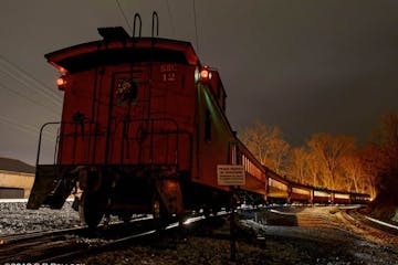 The outside view of the caboose on the train tracks at night.
