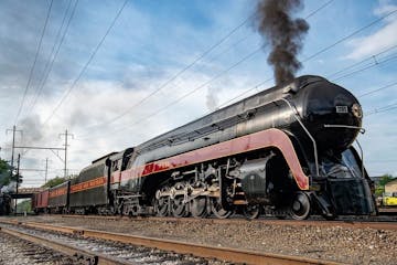A large long train (#611) on a track with smoke coming out of it.