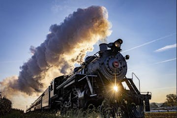 a steam engine is on a train track with smoke coming out of it