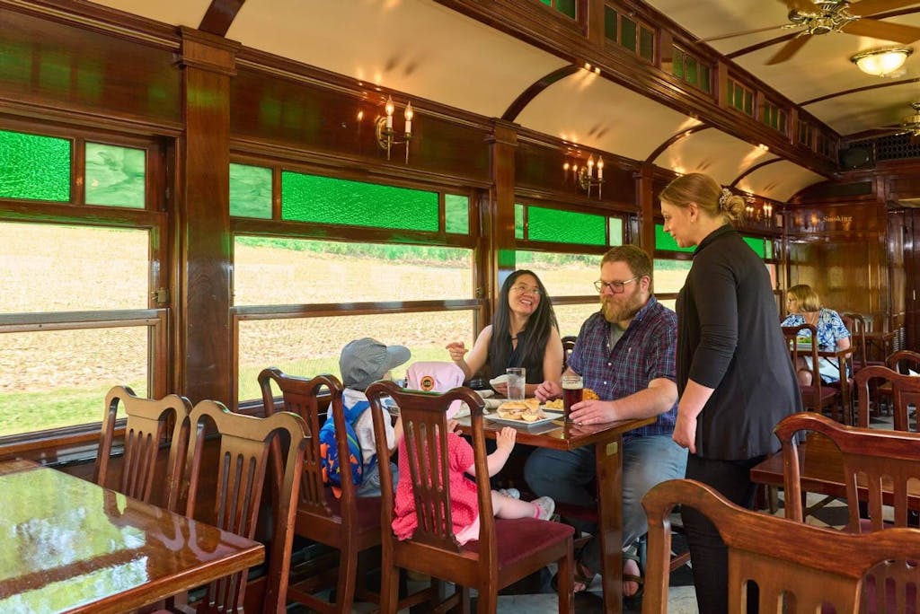 a group of people sitting at a table in a dining car on a passenger train