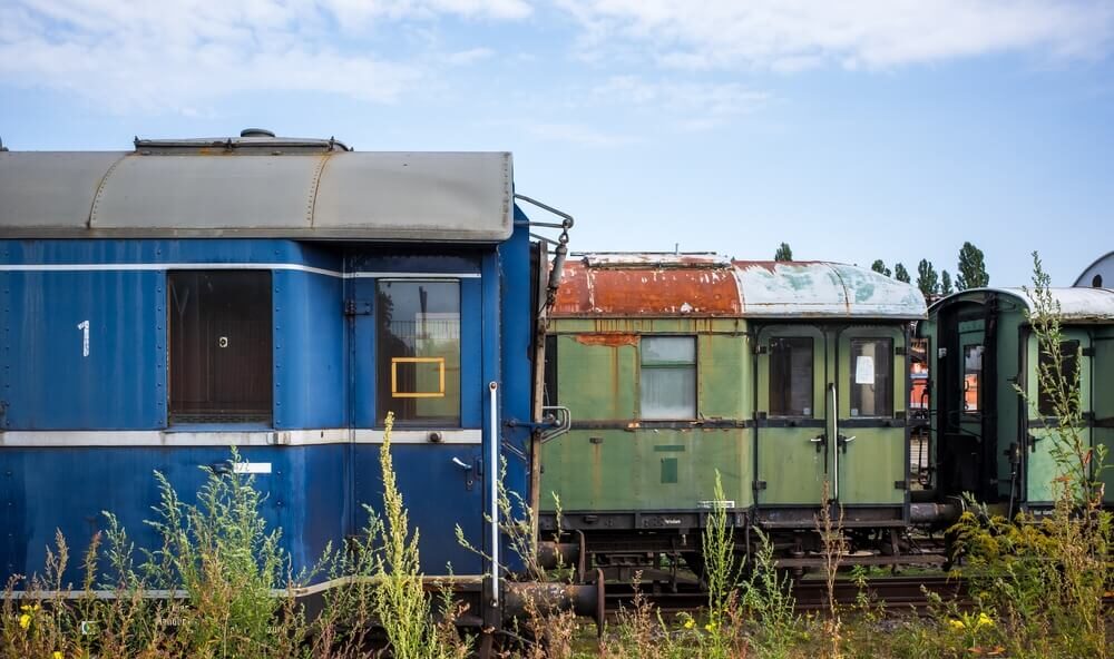An old abandoned train is parked among the grass.