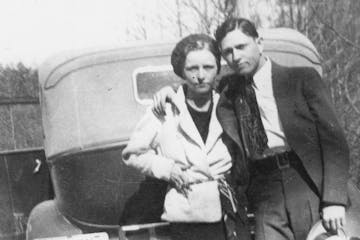 Bonnie Parker standing in front of a car posing for the camera