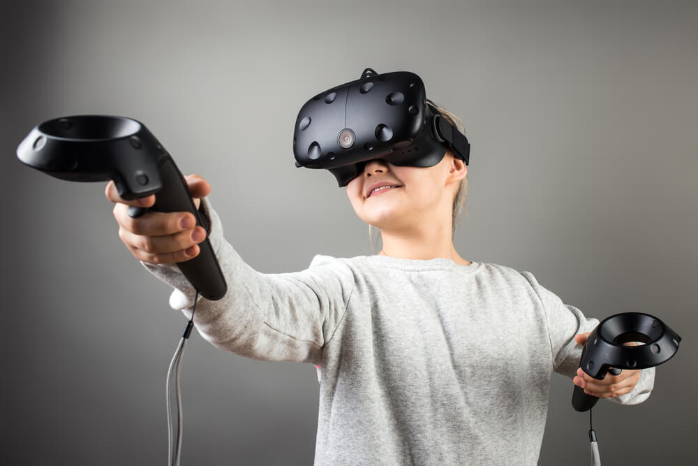 A child wearing virtual reality goggles and using VR controllers.