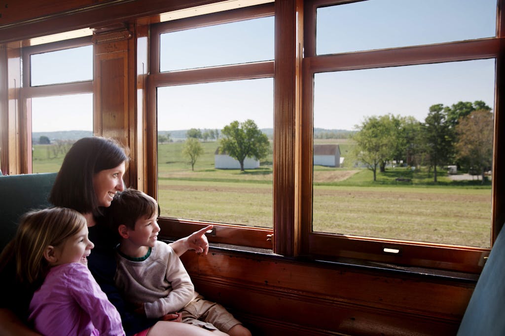 Mother with 2 kids looking out the window of a train.