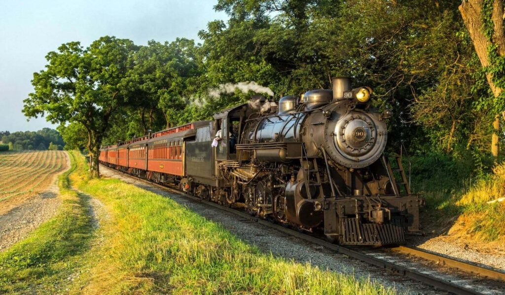 steam engine 90 traveling down train tracks near a forest