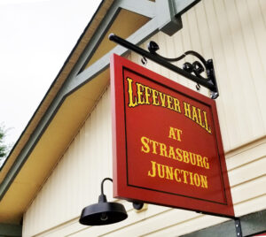 A sign on the side of a building that says Lefever Hall at Strasburg Junction.
