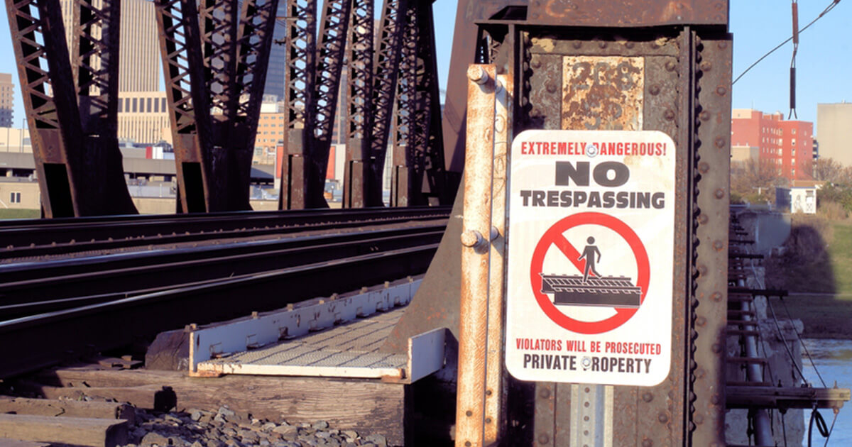 A no trespassing sign on the side of a railroad tracks building.