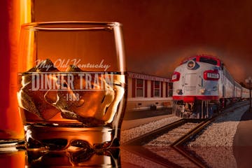 a glass of bourbon next to a train