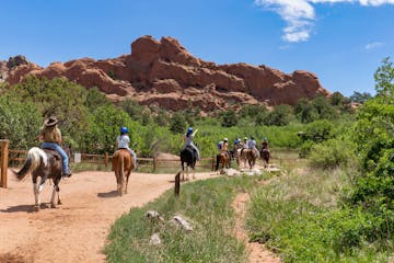 a group of people riding a horse on a dirt road
