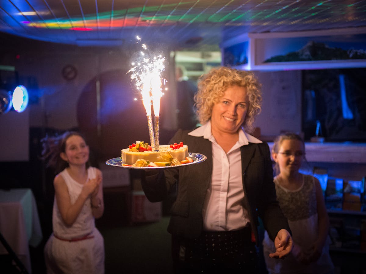 a person standing in front of a cake with lit candles