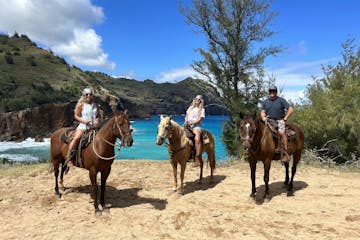 a group of people riding horseback on a beach