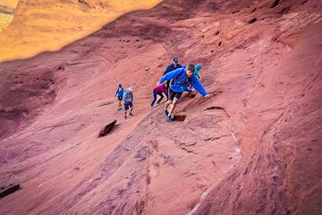 a group of people walking up a desert sandstone