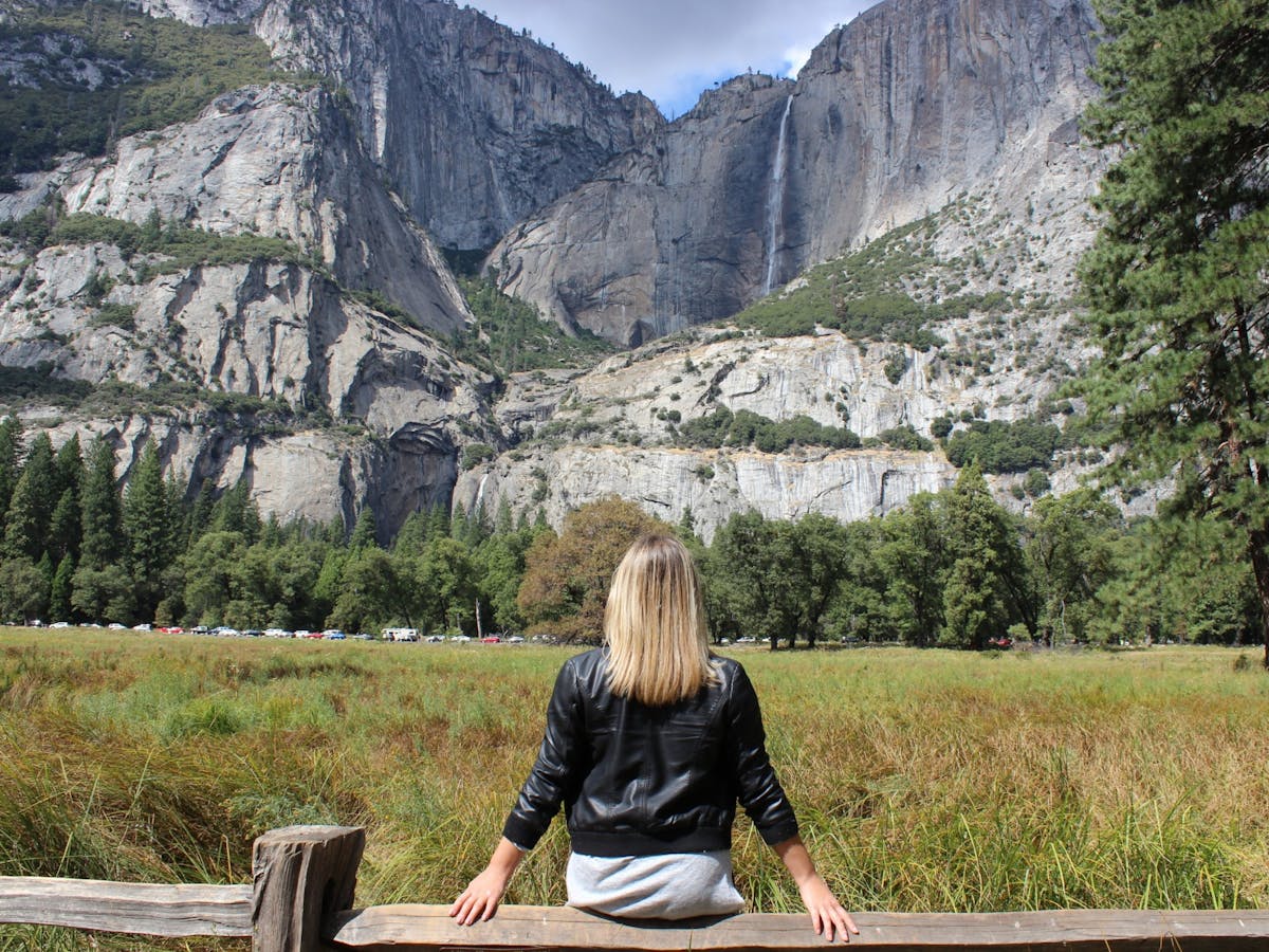 woman sitting on wood fence looking out to yosemite national park