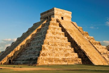 a large brick building with Chichen Itza in the background