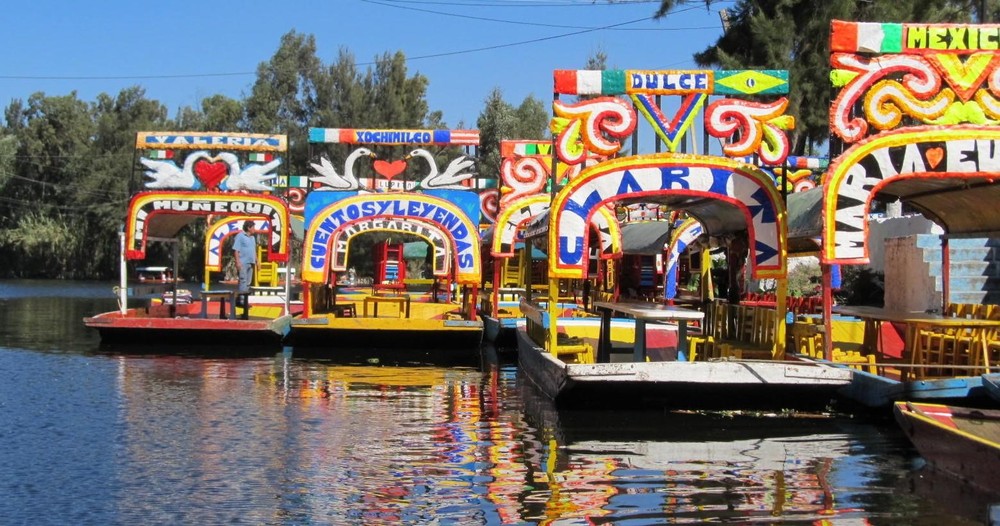 a boat that is floating in the water with Xochimilco in the background