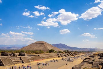 a group of people in a desert area with Teotihuacan in the background