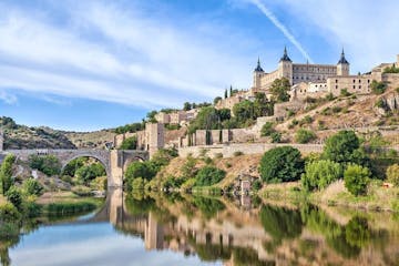 a castle on top of a body of water with Toledo in the background